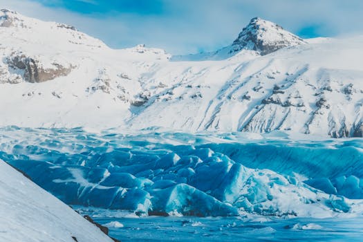 Breathtaking view of a snowy mountain with a striking blue glacier under a clear sky.