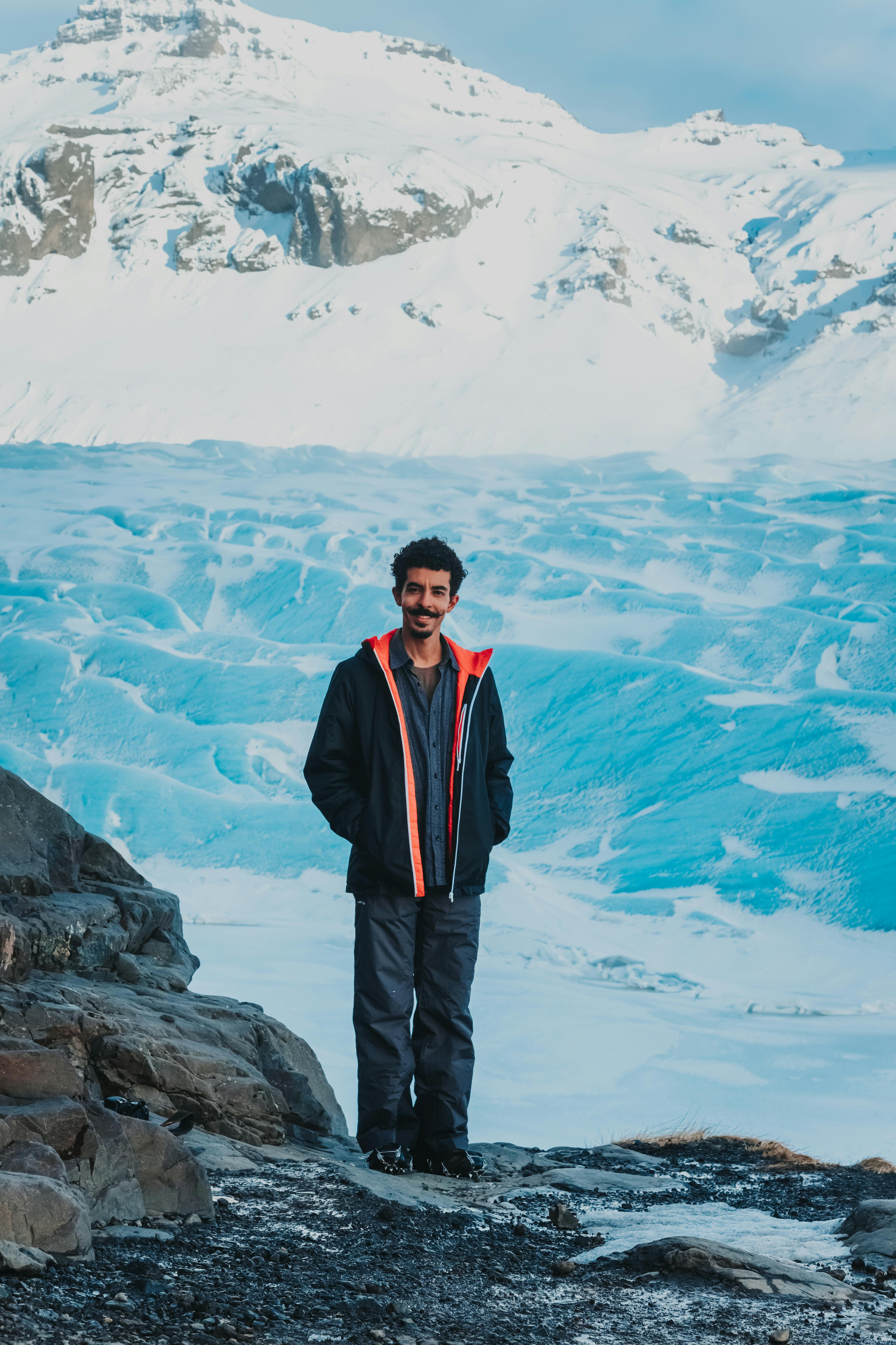 Prescription Goggle Inserts - A man standing on the edge of a glacier, surrounded by a snowy mountain landscape, embracing the winter adventure.