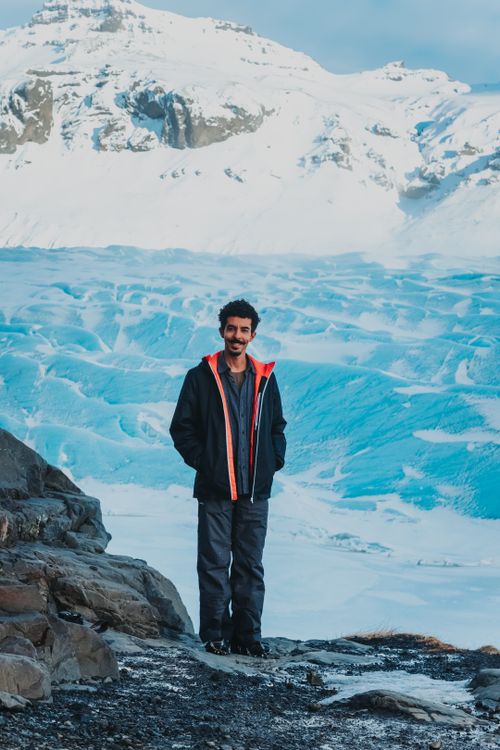 Free Full body of man with black hair standing on edge of cliff near quarry against snowy mountain during cold day Stock Photo