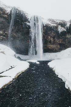 寒冷汹涌的河流上飘着雪，高耸的岩石悬崖上挂着雄伟的瀑布