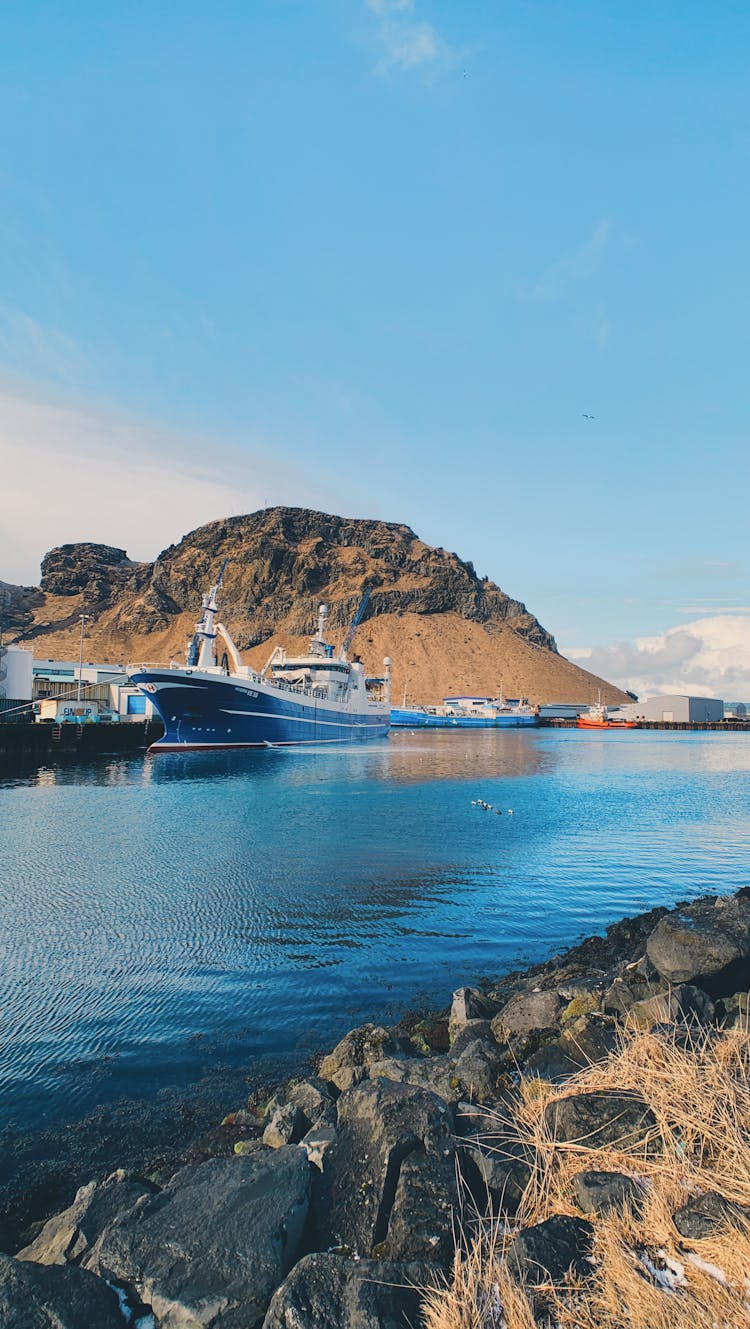 Moored Ship In Fjord With Rocky Cliffs