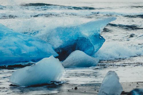 Free Crystal ice chunks on remote empty shoreline with cold foam waves running on ground Stock Photo