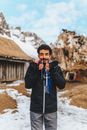 Funny ethnic male in warm jacket making grimace with icicle tusks in mouth looking away against cold nature