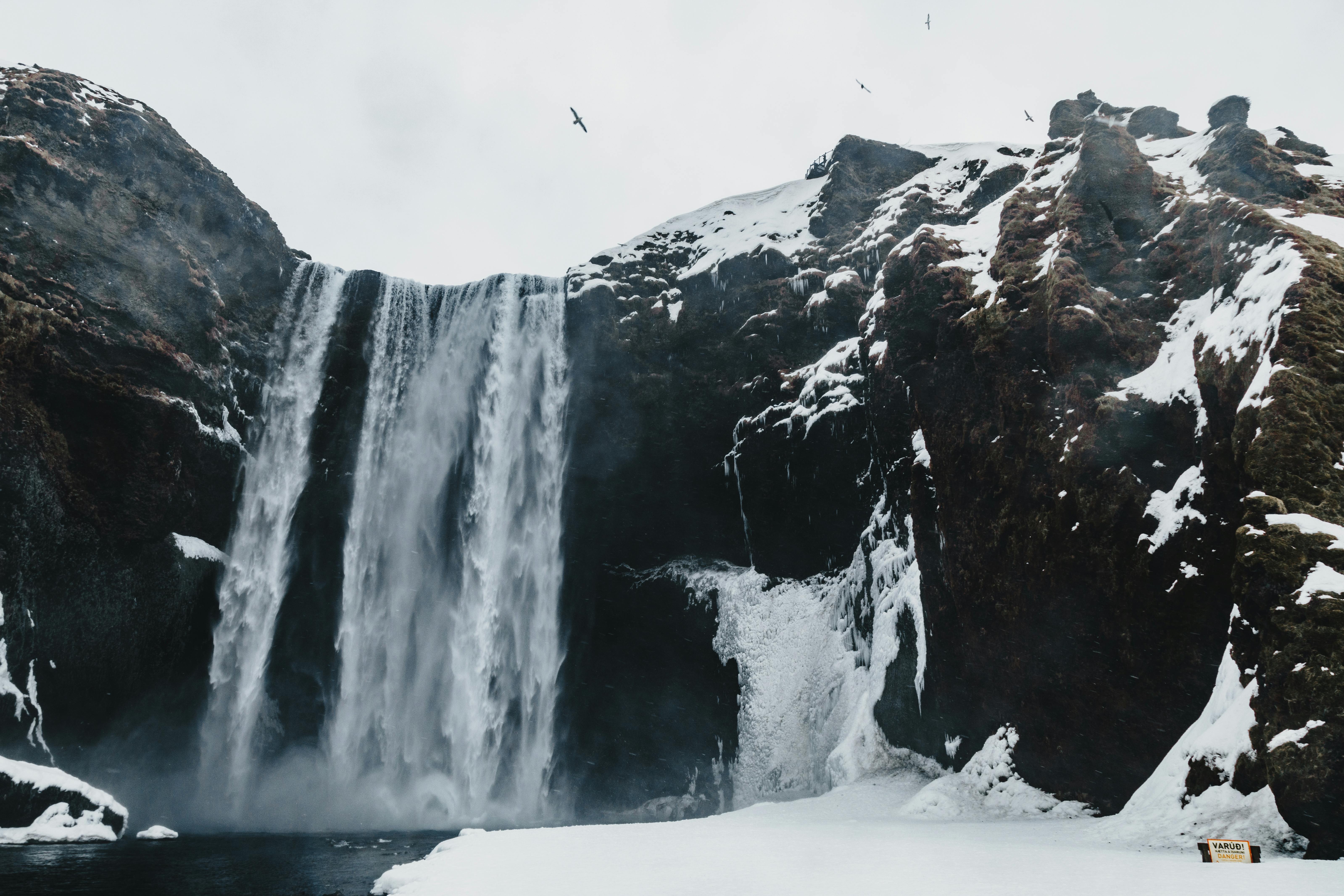 fast waterfall in snowy mountains under sky