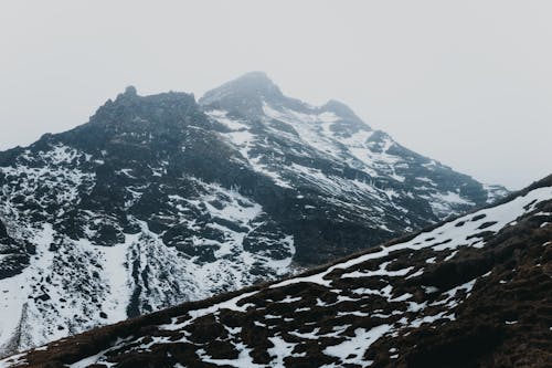 Snowy mountains under sky on foggy day