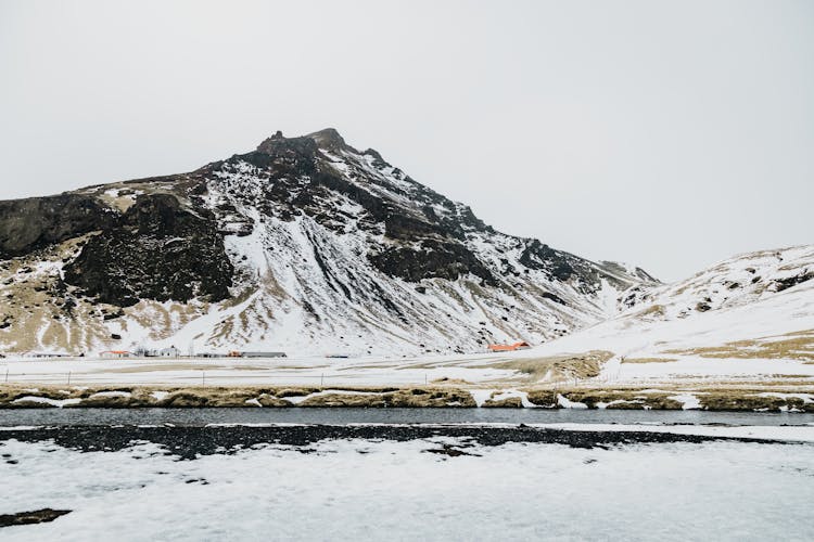 High Snowy Ridge Near River Under Sky