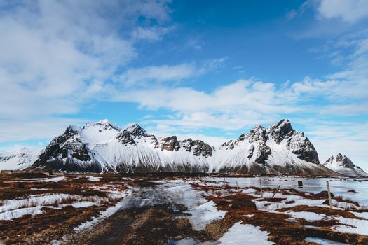 Rocks near sea and snowy terrain under sky