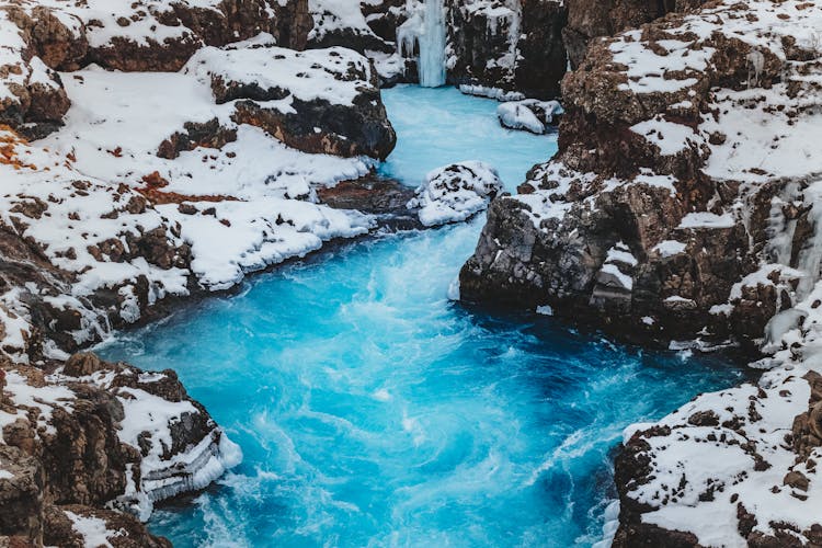 Bright Blue River Between Snowy Cliffs In Wintertime