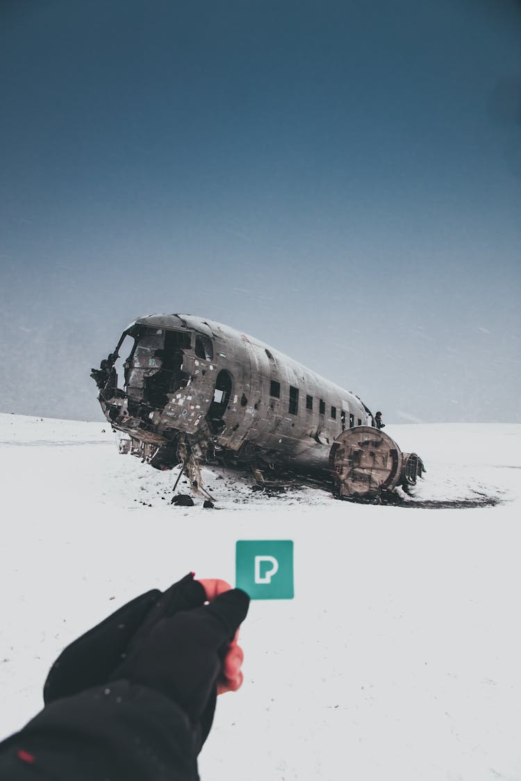 Faceless Person Showing Sticker Against Crashed Airplane In Winter