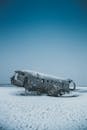 一架飞机的残骸荒凉地静卧在白雪皑皑的宁静风景中，唤起了孤独与历史的魅力
