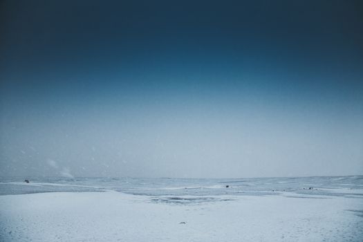 Endless sea with splattering water and horizon line near snowy coast under sky in wintertime