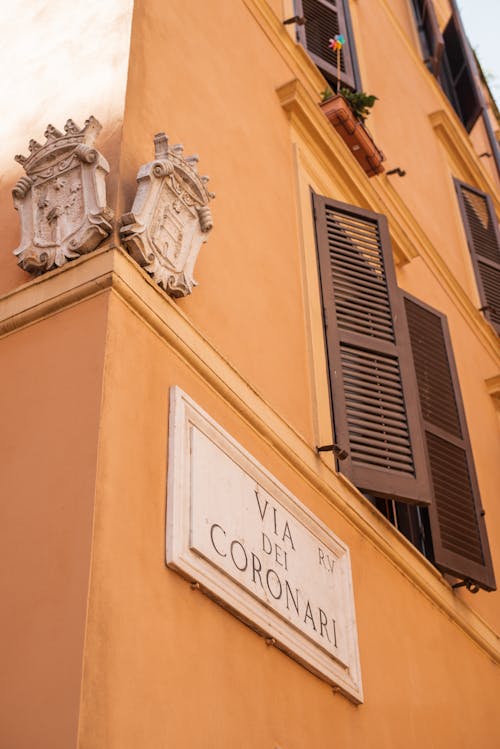 Low angle of corner of orange building with typical Italian wooden shutters on Via dei Coronari in historic center of Rome on sunny day