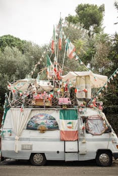 A uniquely decorated vintage camper van with flags and trinkets parked outdoors.