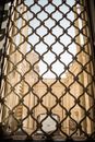 Decorative lattice window overlooking inner yard of cream colored building on sunny day