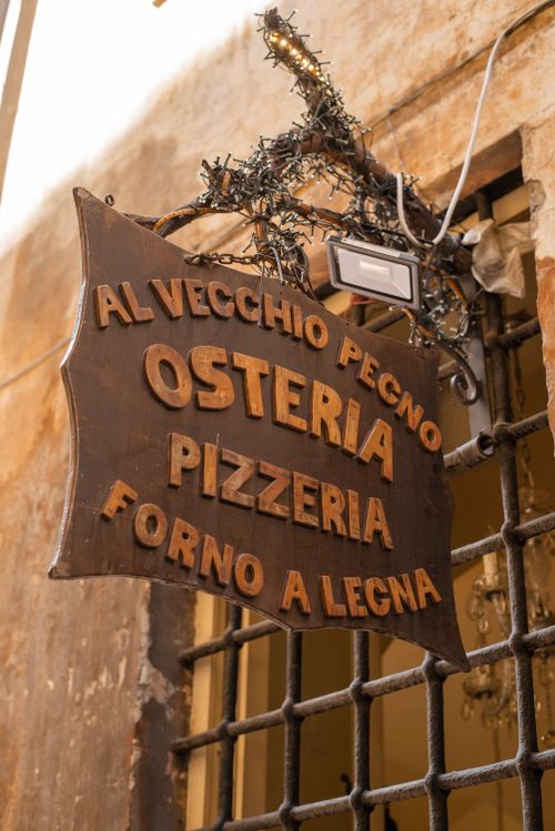 Free From below wooden sign of Italian pizzeria attached on window treillage during sunny summer day Stock Photo