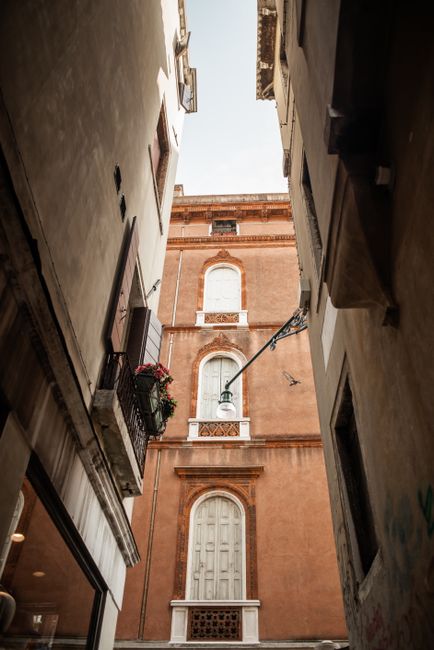Low angle exterior of narrow street with old medieval stone buildings decorated with cute small windows and balconies in Europe