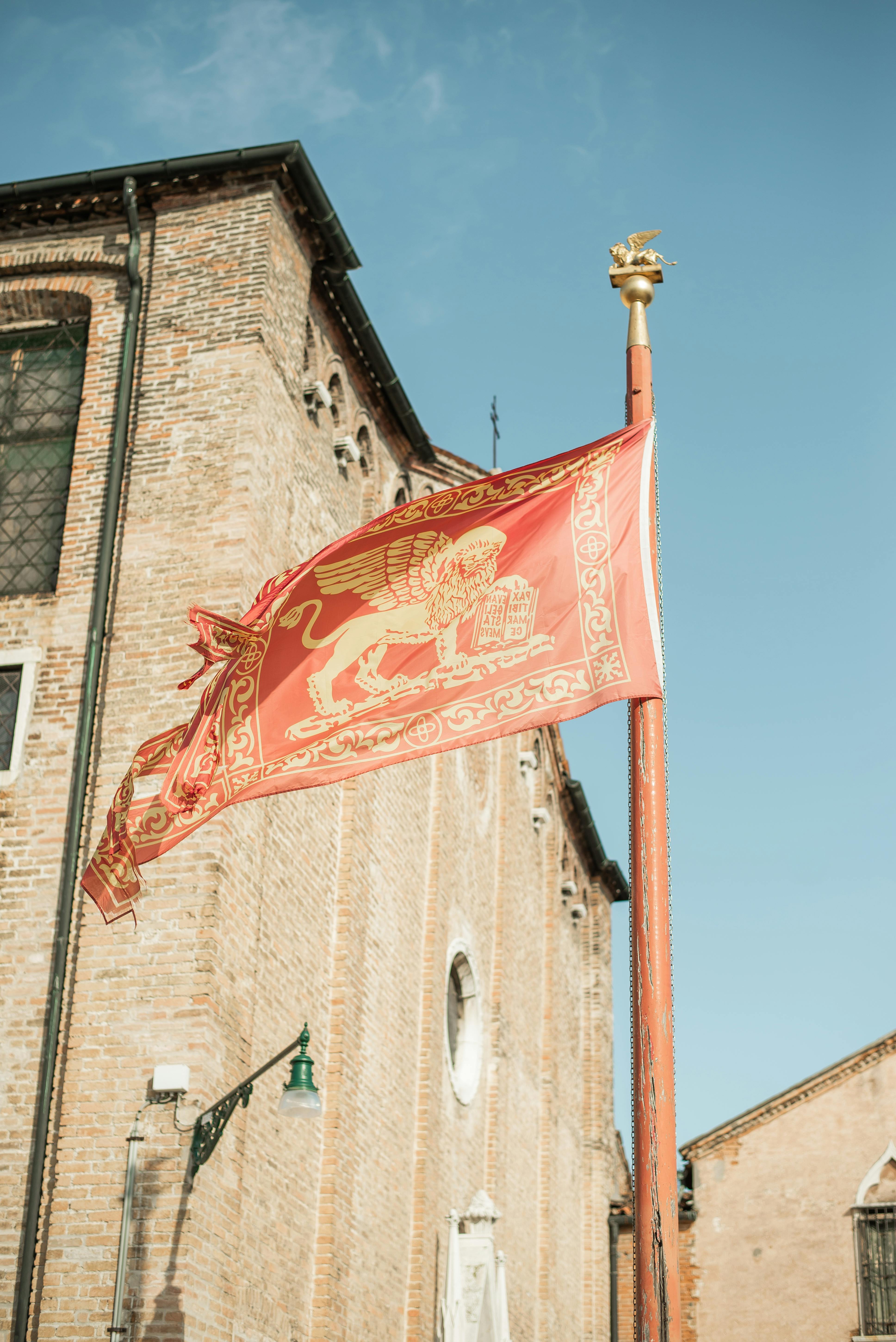 Waving flag of Venice against historical building · Free Stock Photo