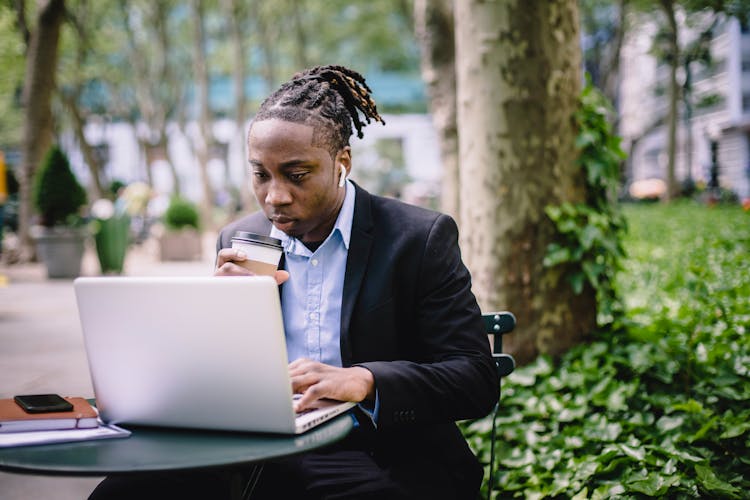 Thoughtful Black Businessman Using Laptop In Park