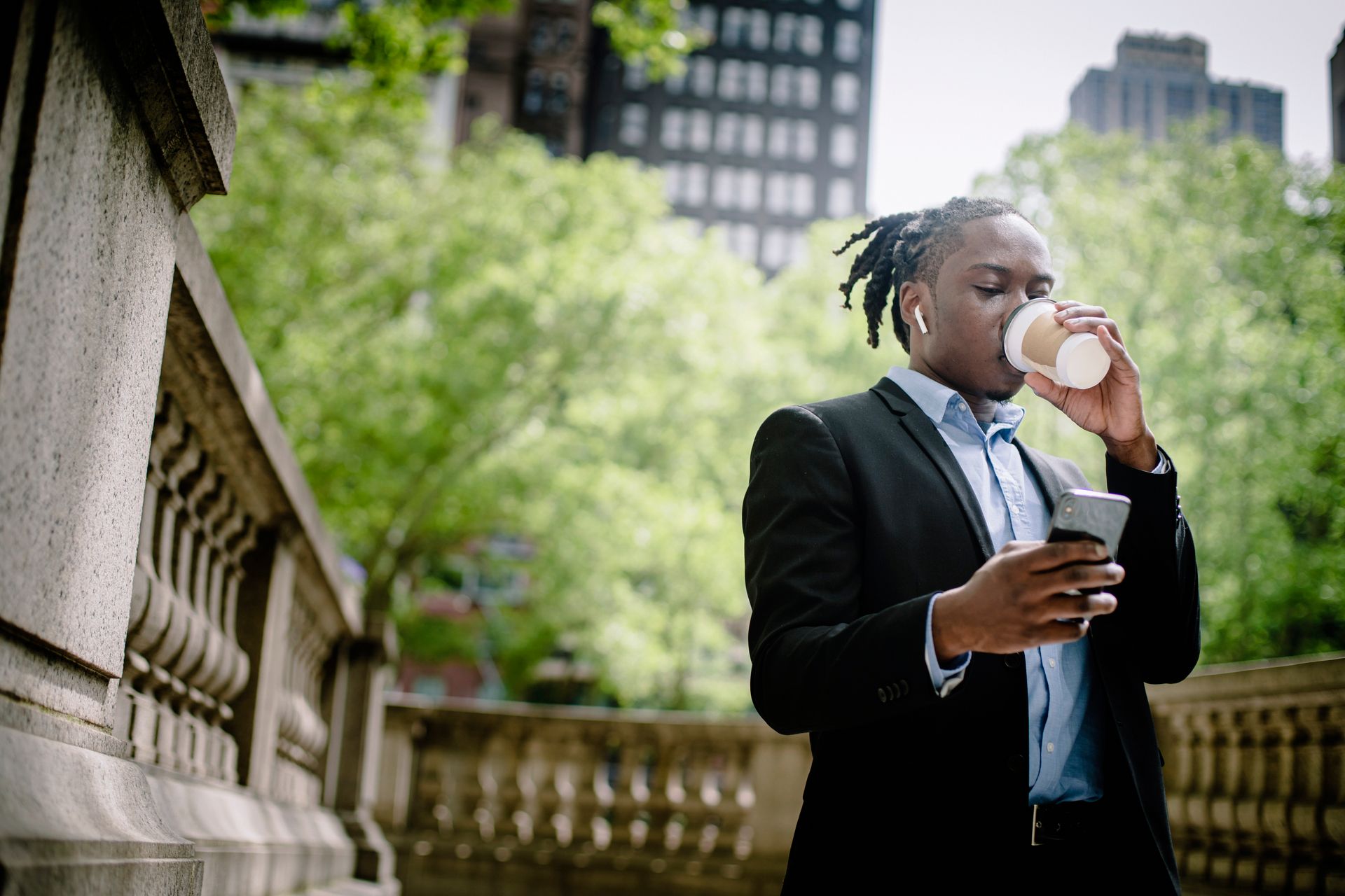 Concentrated young male using smartphone during coffee break on street