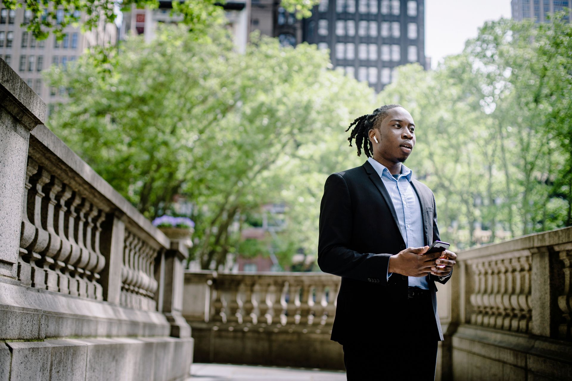 Young professional in a suit speaking on the phone outdoors with urban backdrop, focused and engaged.
