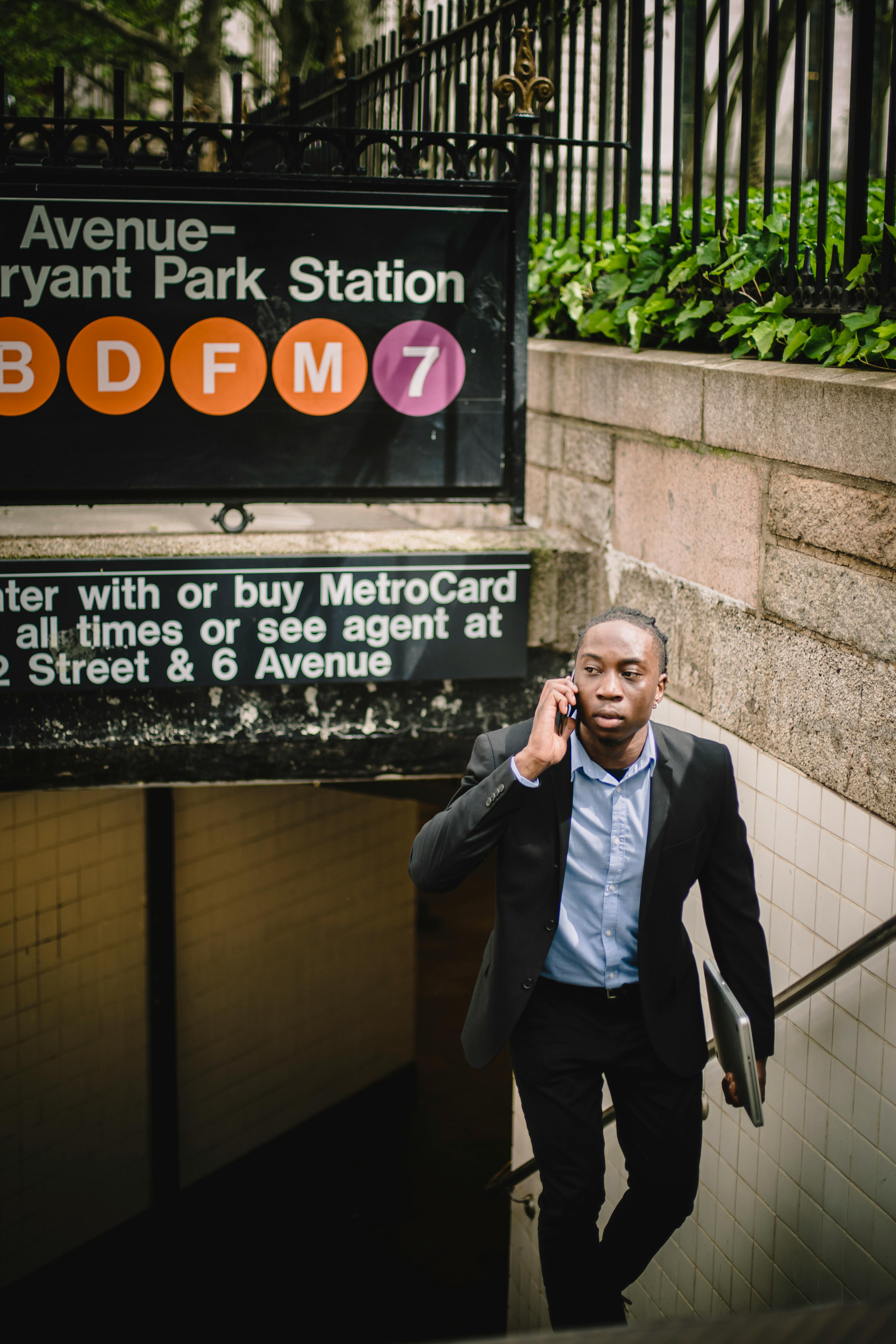 serious man climbing stairs of subway station and talking on smartphone