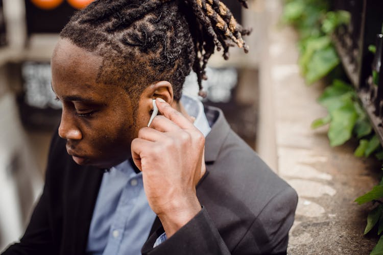 Young Black Male In Suit Listening To Music On Street