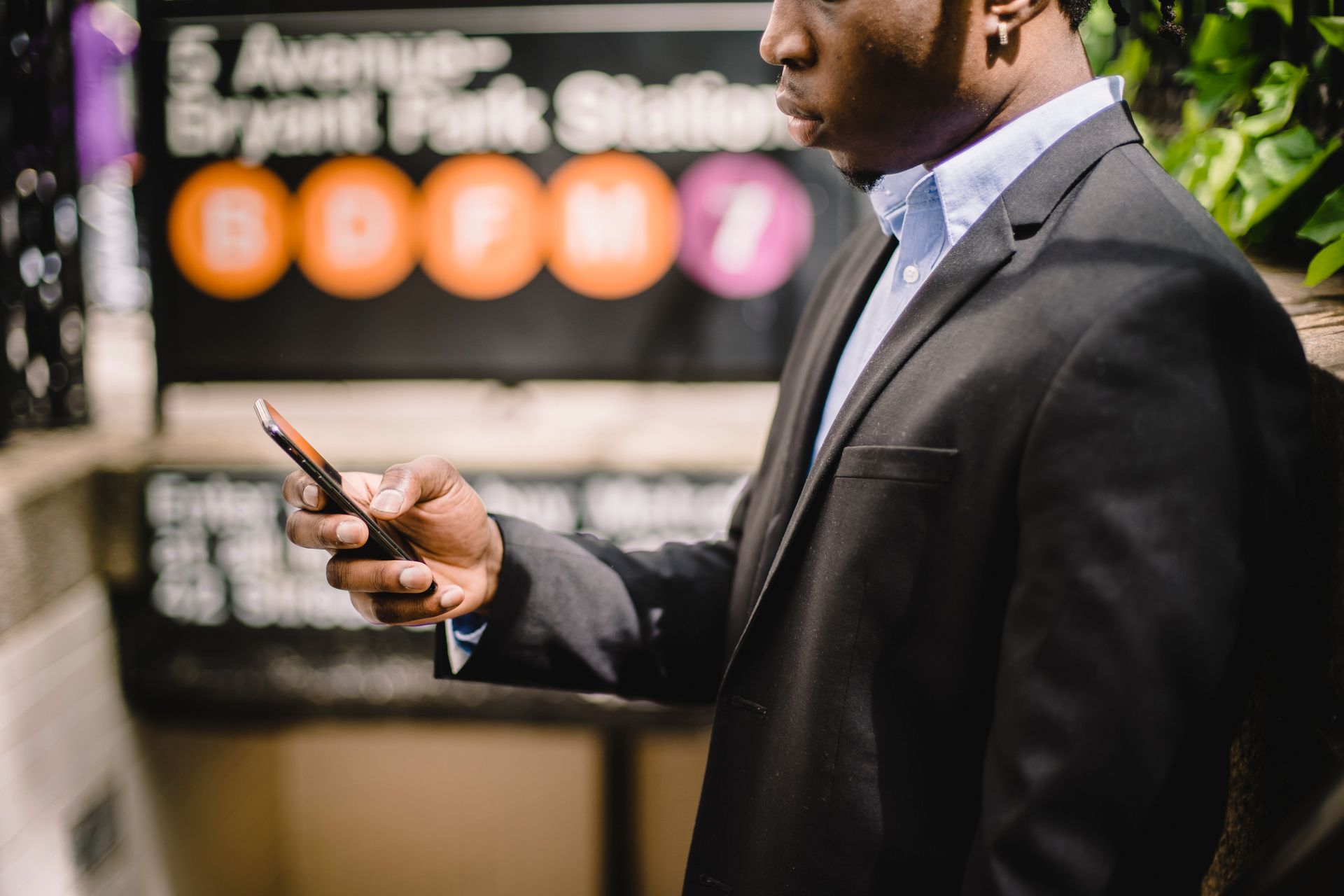 Professional man texting on his smartphone outside Bryant Park Station, New York City.