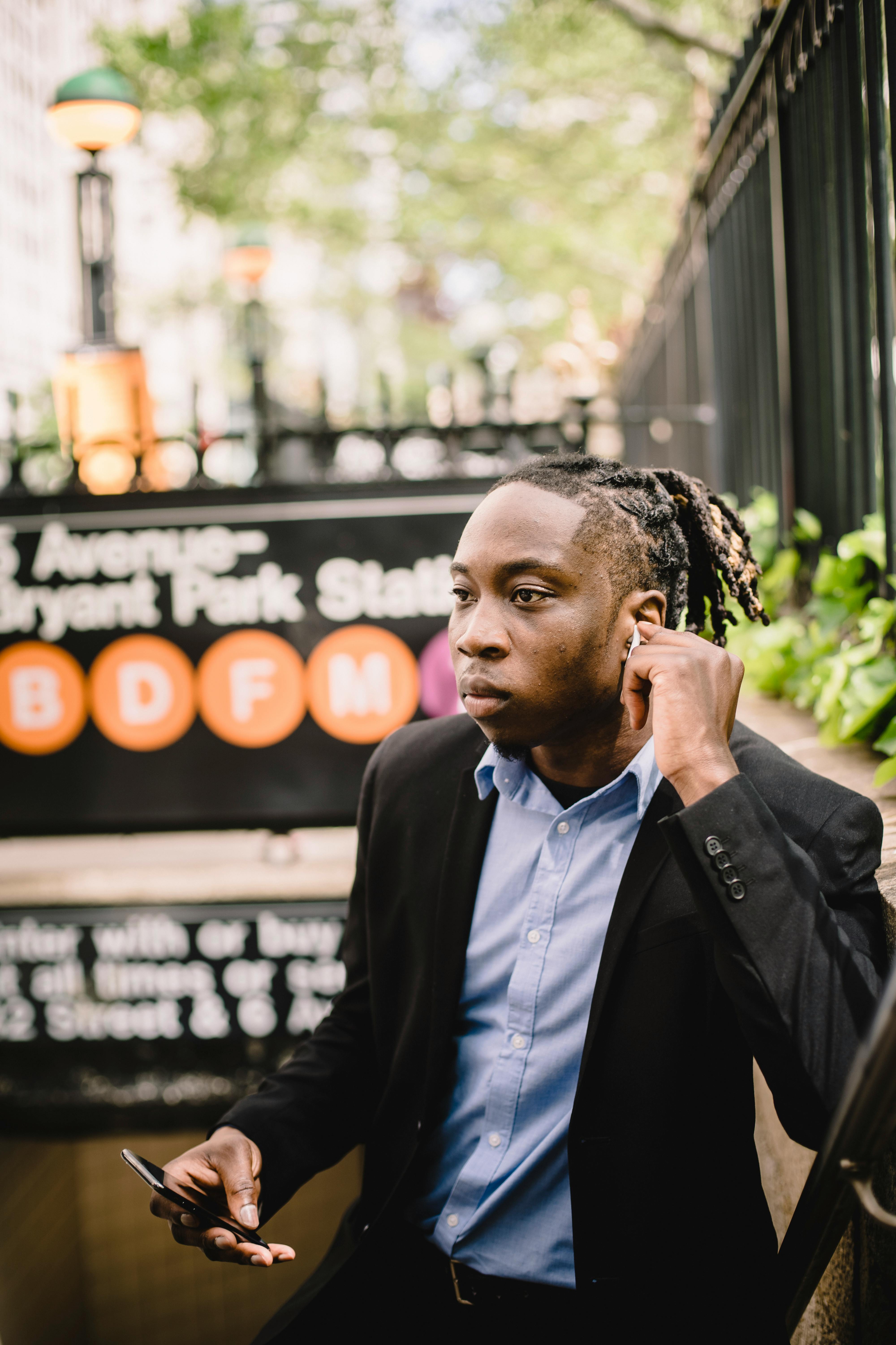 young black office worker listening to music through wireless earbuds