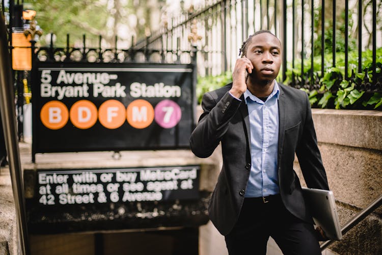 Serious Black Businessman Talking On Smartphone On Street