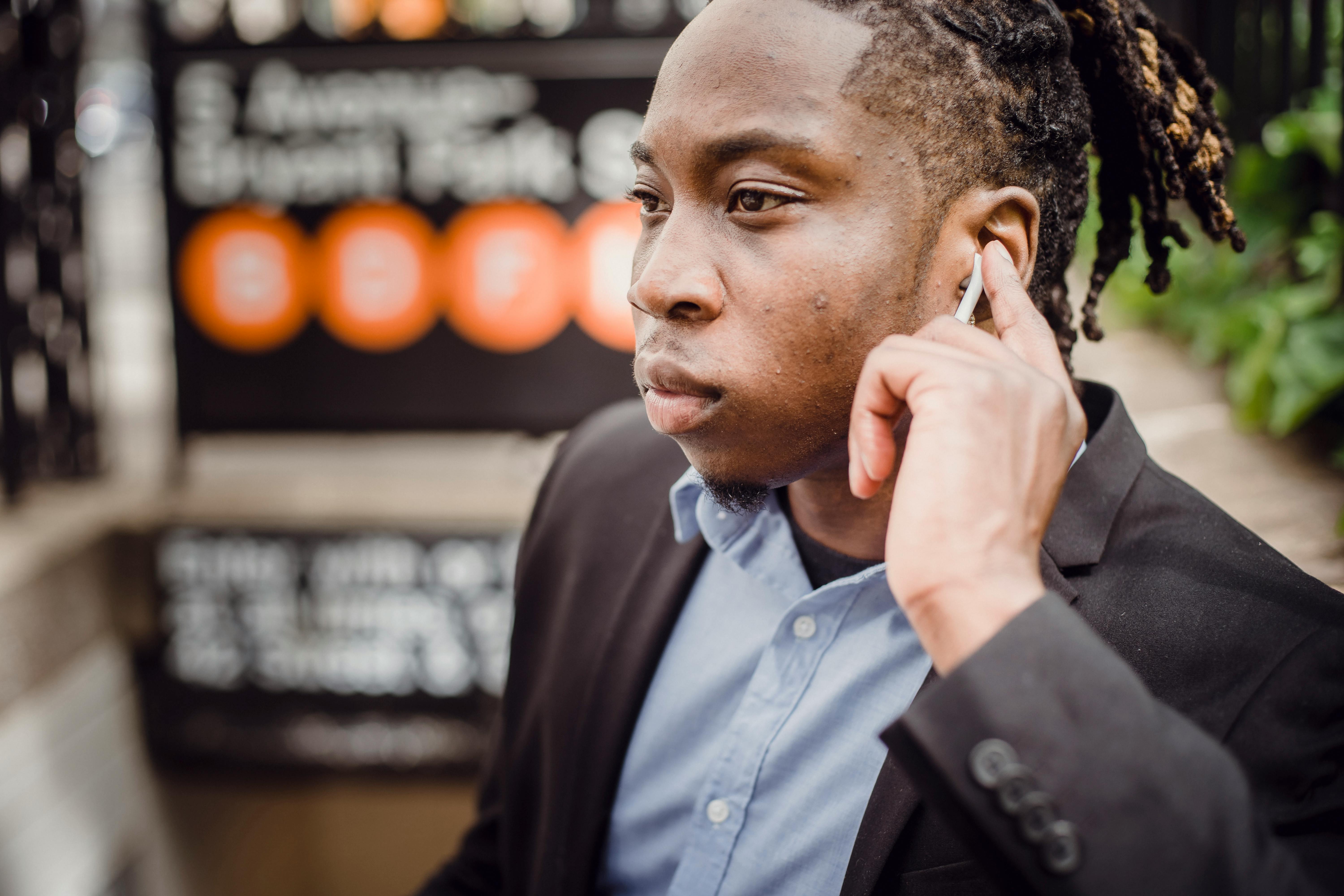 Concentrated ethnic man with earbuds on street