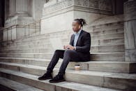 自信的商人坐在城市台阶上，专注地用笔记本电脑工作