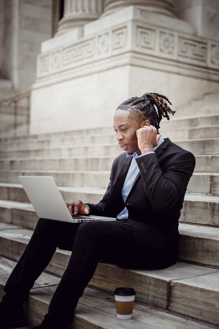 Content Black Businessman Using Laptop On Building Stairs