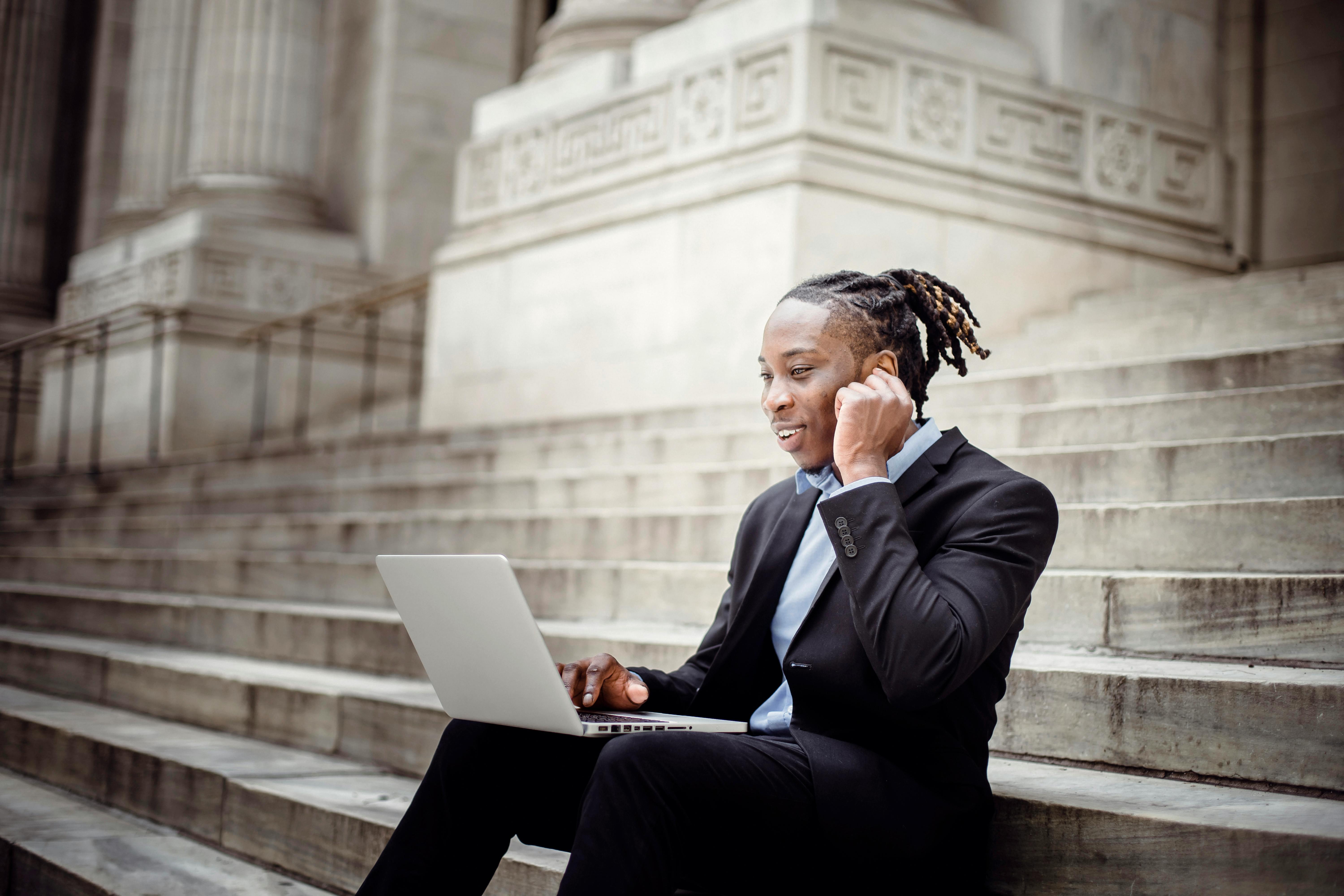 happy black businessman having video call on stairs