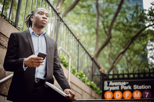 Thoughtful African American businessman using smartphone near metro station