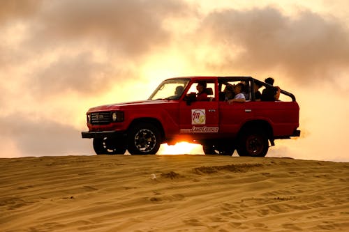 People Riding a Red 4x4 Vehicle on Desert