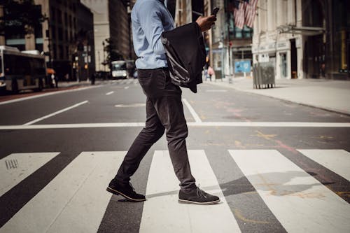 Crop stylish man walking on crosswalk in downtown