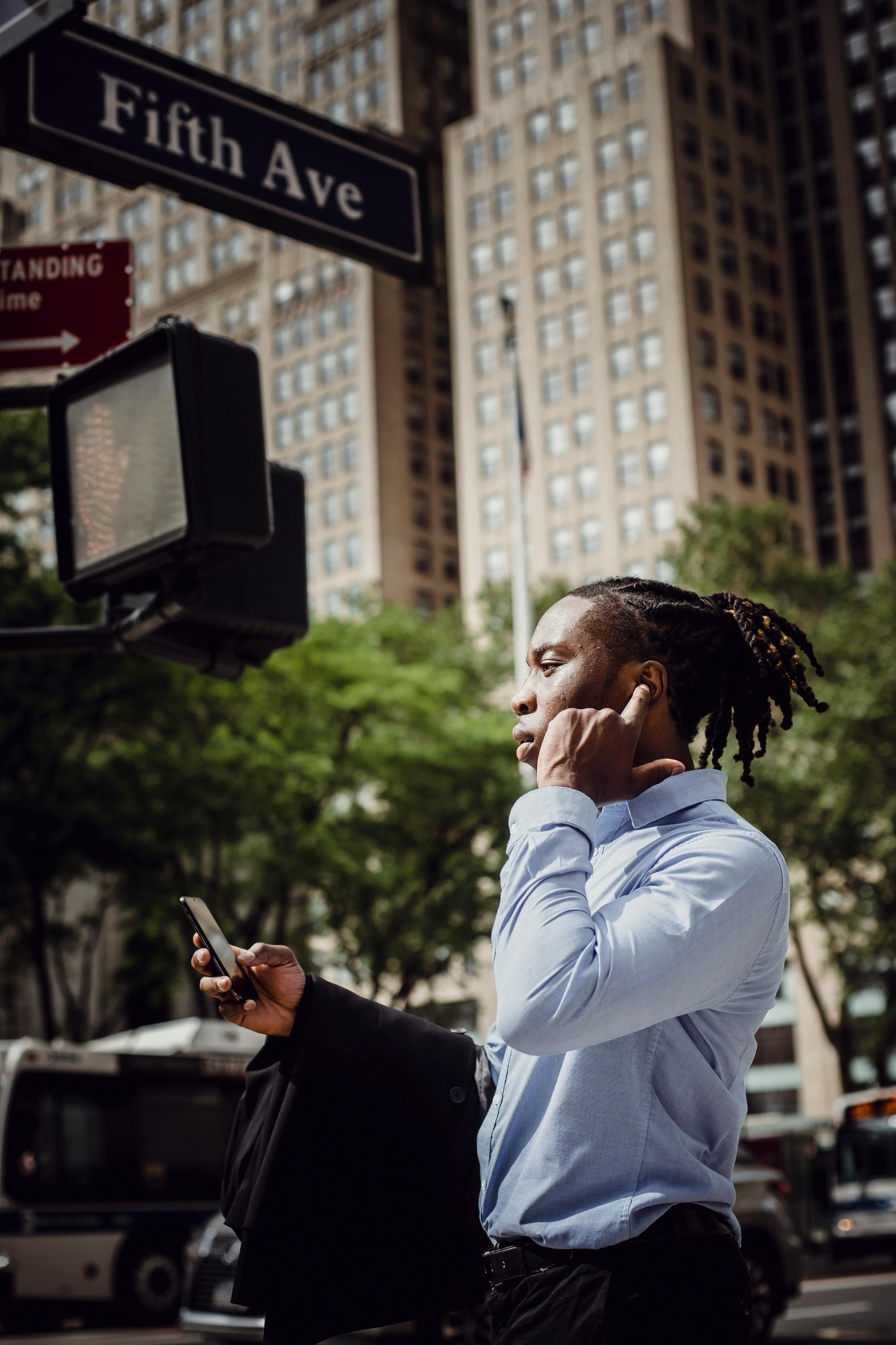 confident ethnic entrepreneur talking on cellphone in downtown on sunny day