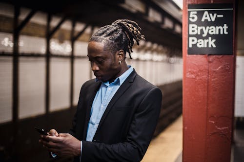 Serious young man using smartphone while waiting for metro train