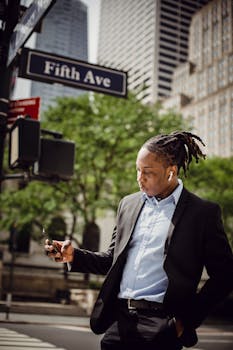 Young professional checking smartphone on sunny Fifth Ave in NYC.