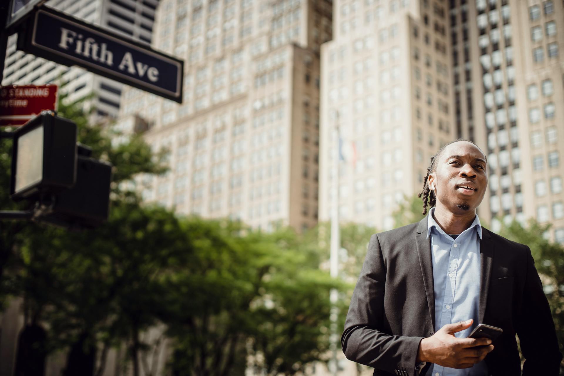 Young office employee listening to music on Manhattan street