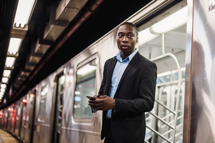 Modern Male In Office Suit With Smartphone Getting Off Train