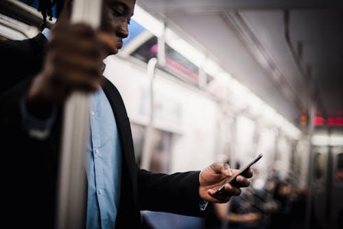 Free Black man using mobile while commuting by train Stock Photo