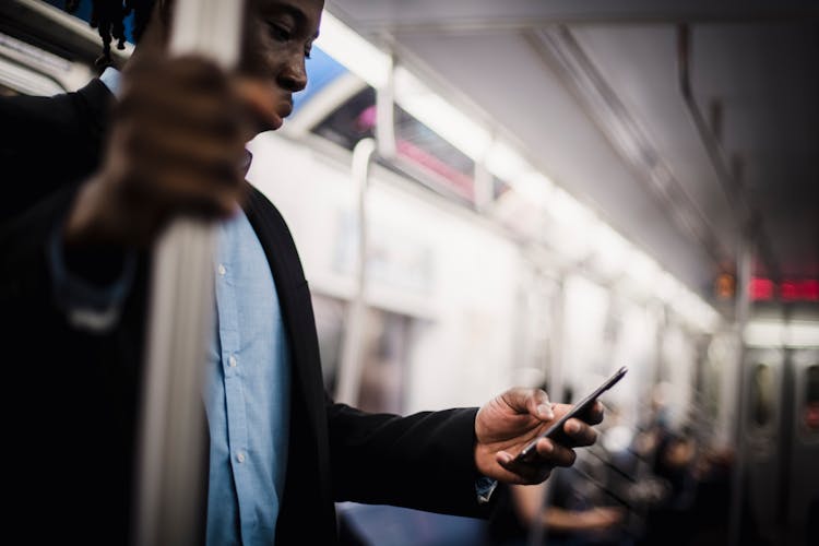 Black Man Using Mobile While Commuting By Train