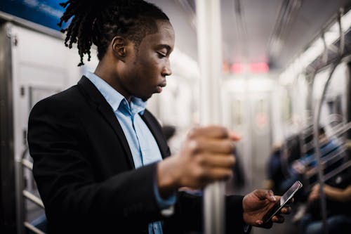 Young African American man using smartphone on train