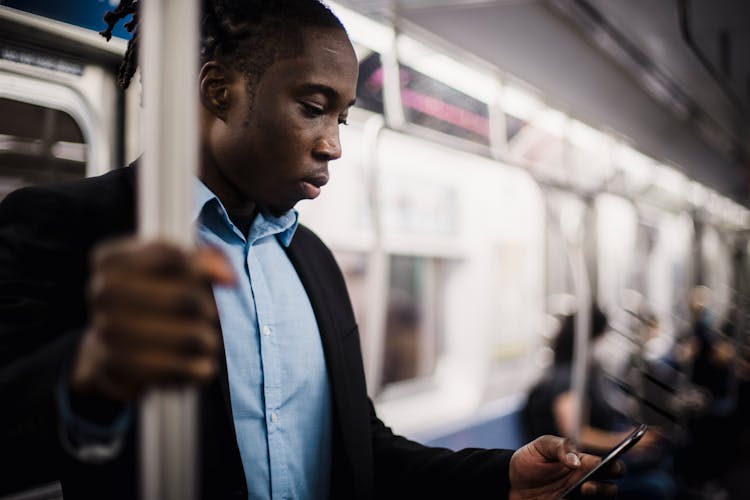 African American Office Worker Using Smartphone While Commuting By Train