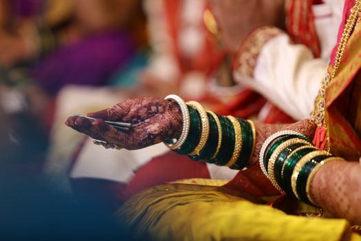Intricate henna designs and traditional bangles on a bride's hand during an Indian wedding ceremony.