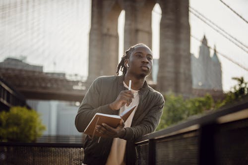 Serious African American guy with planner waiting for meting with planner in downtown