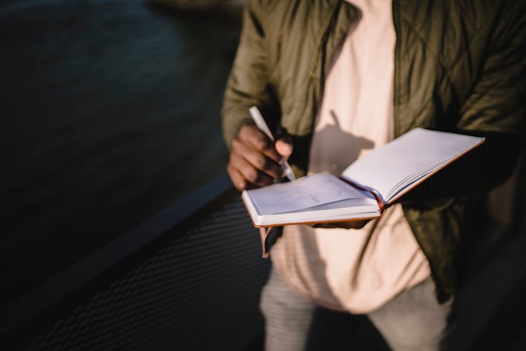 Unrecognizable Man Writing Notes In Notebook