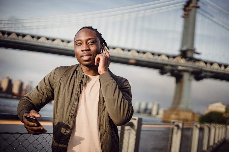 Black Man Talking On Cellphone Through Wireless Earphones