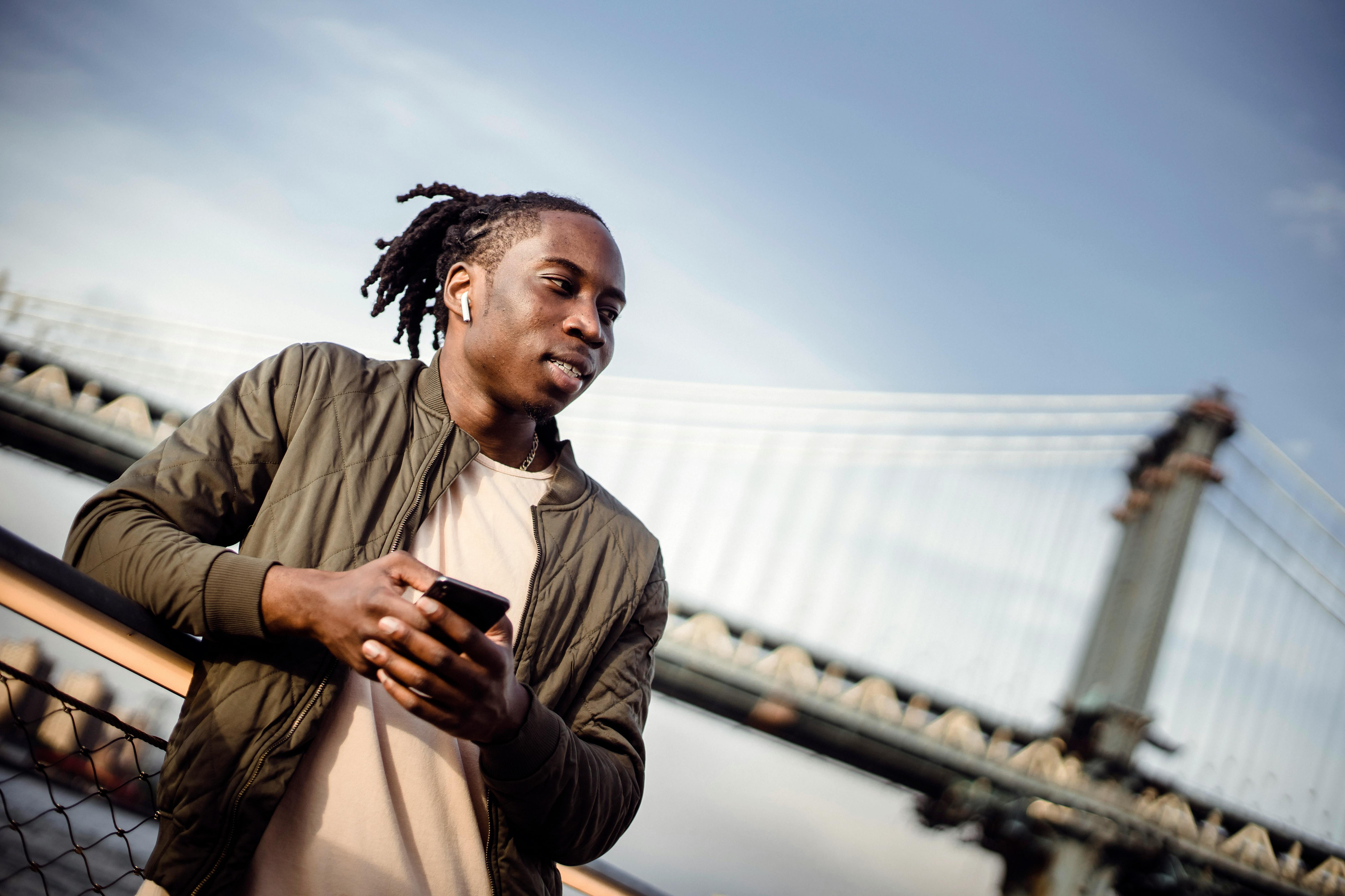 positive black man using smartphone outdoors